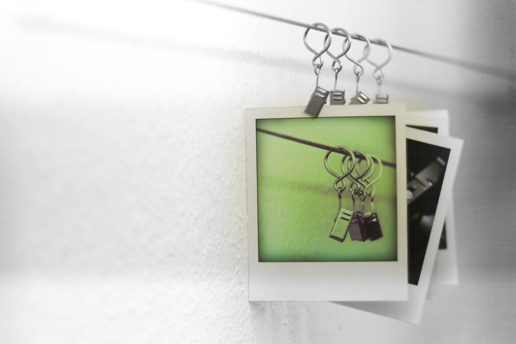 Fotos hängen bei Weißlicht zum Trocknen mit Klammern fixiert an einer Leine in der Dunkelkammer.
