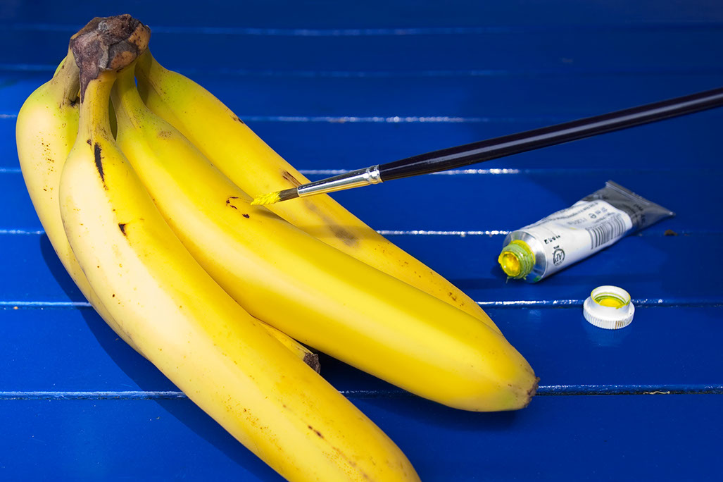 Fleckige Bananenschale wird mit Pinsel und Farbe retuschiert.